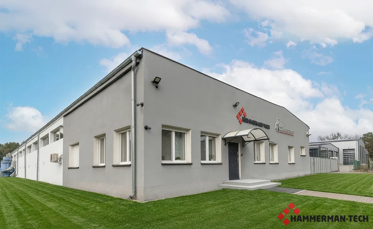 Firmengebäude mit Hammerman-Tech Logo und gepflegtem Rasen vor blauem Himmel, Produktionsstandort